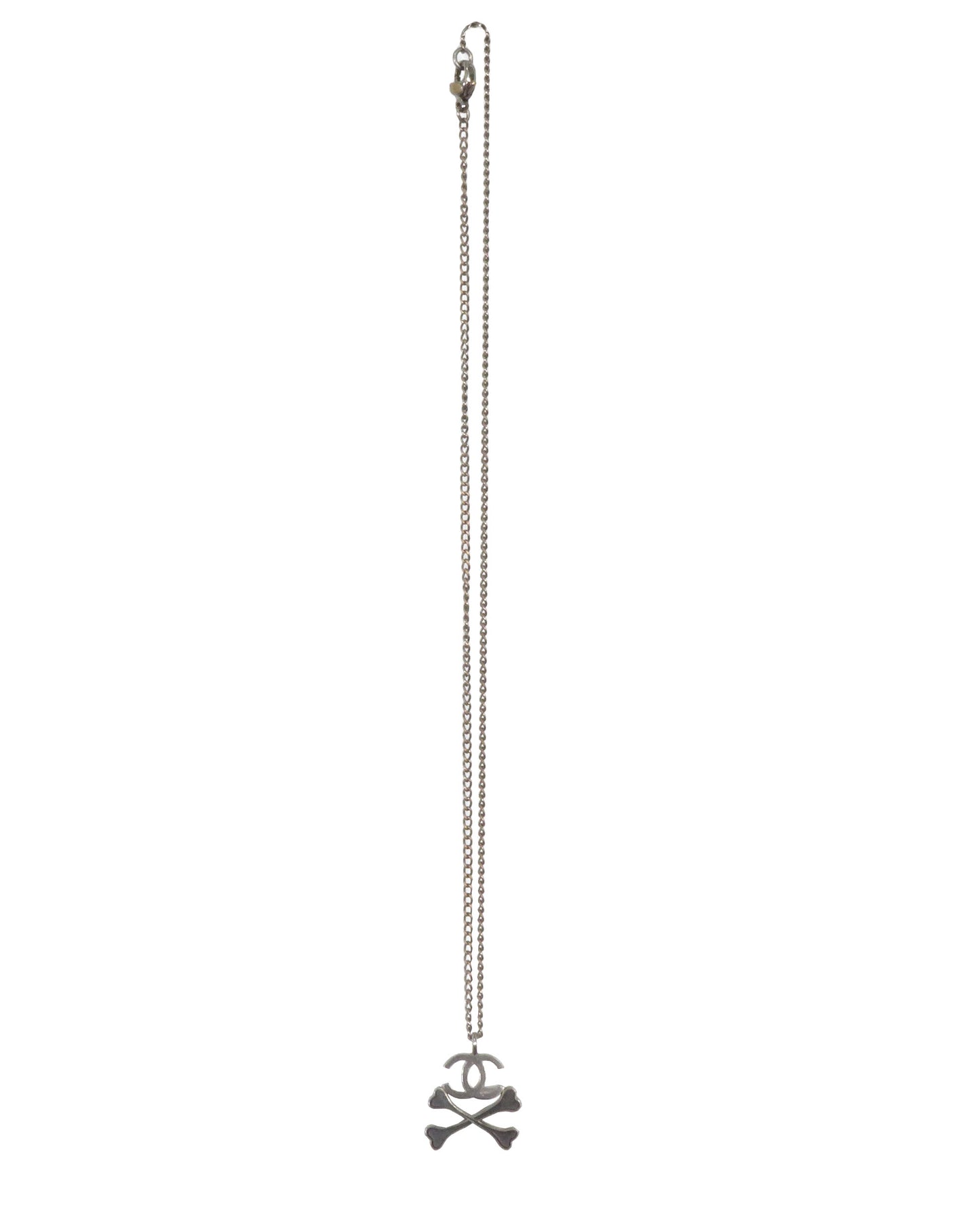 Silver necklace with a pendant on a white background. Chanel FW2003 Skull and Crossbones CC Logo Necklace. - vothe archive - curated designer vintage