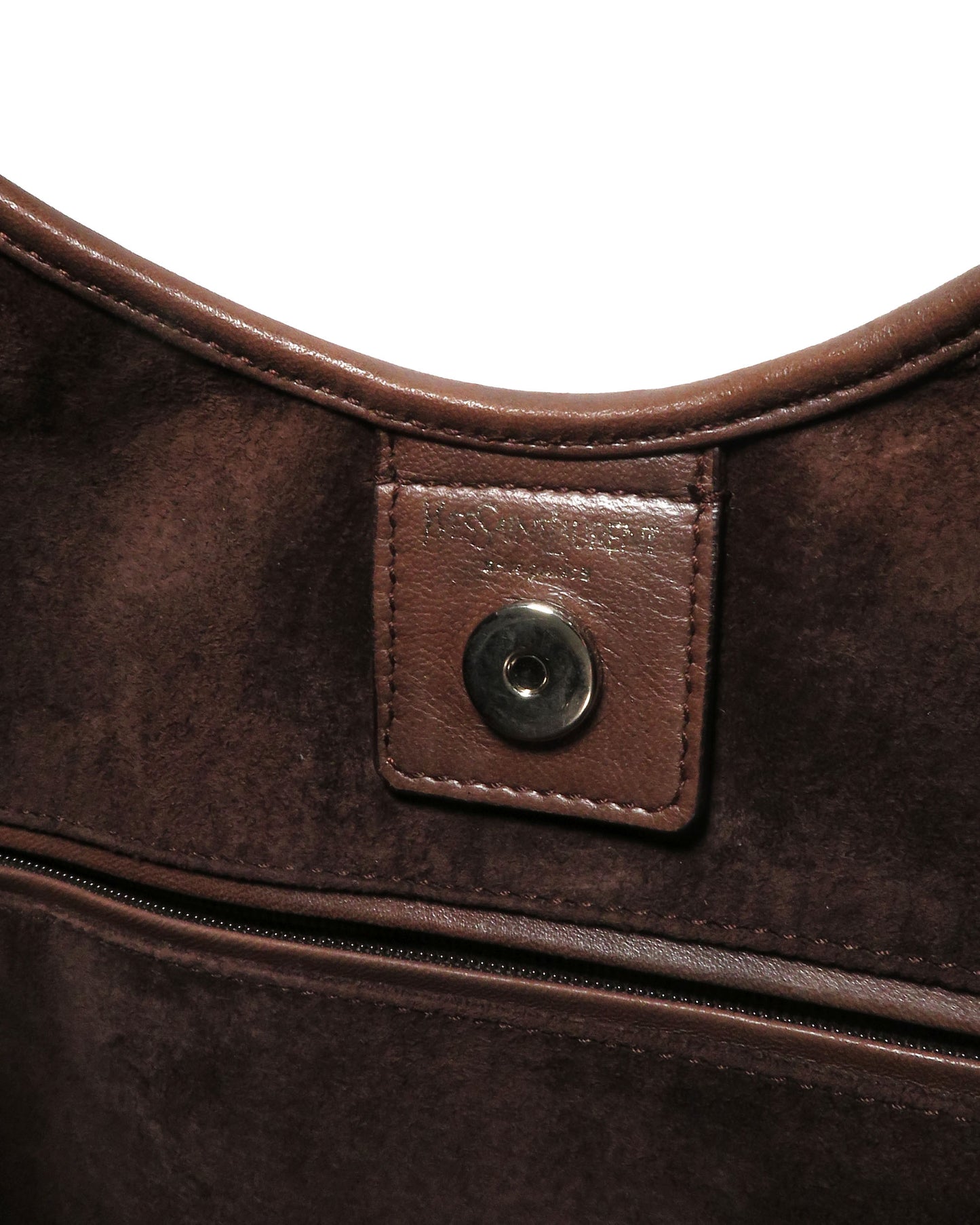 Close-up of a brown leather bag with a button detail on a white background