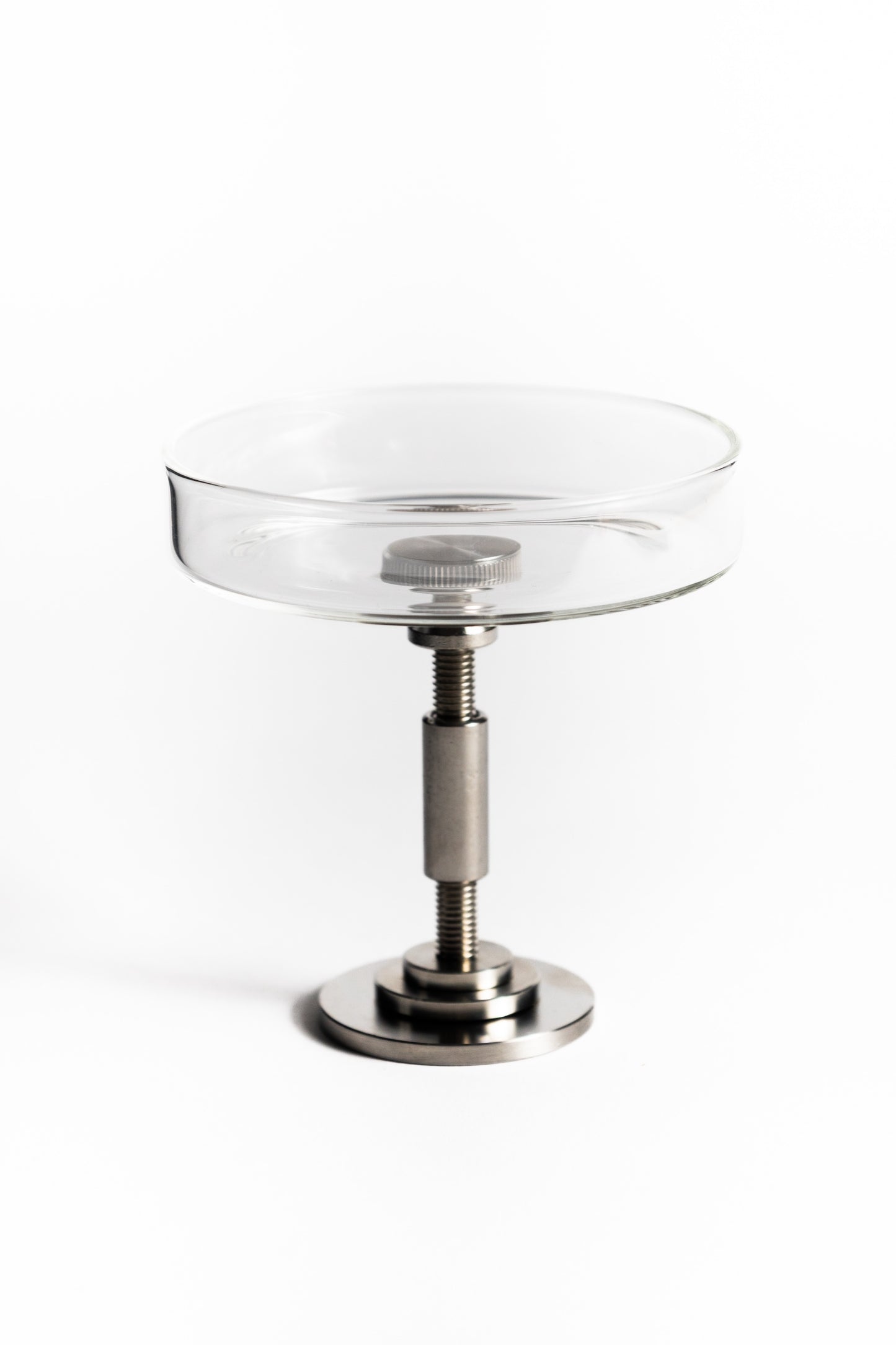 Clear glass dish with metal stand on a white background