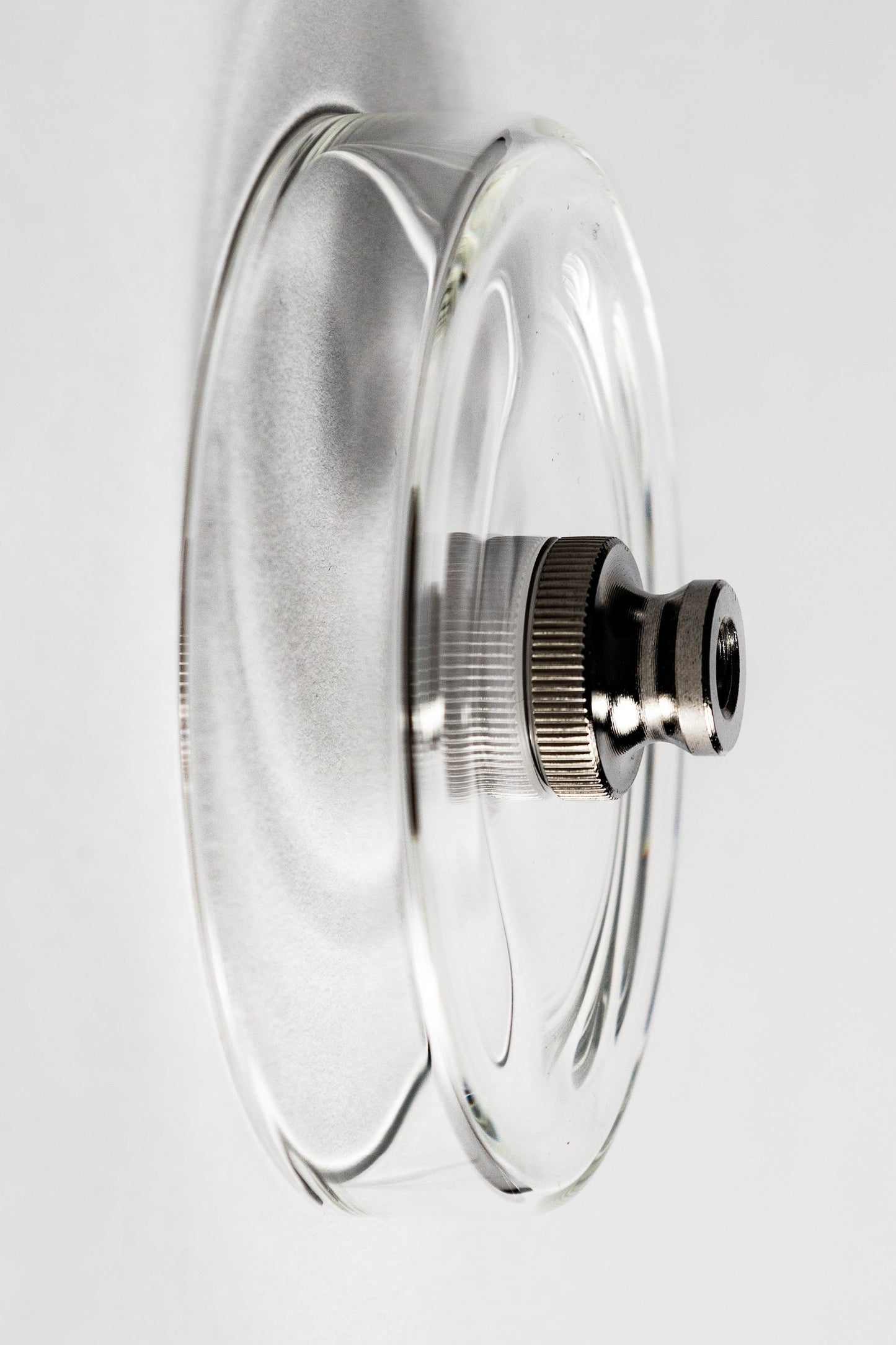 Clear glass lid with metallic knob on a white background