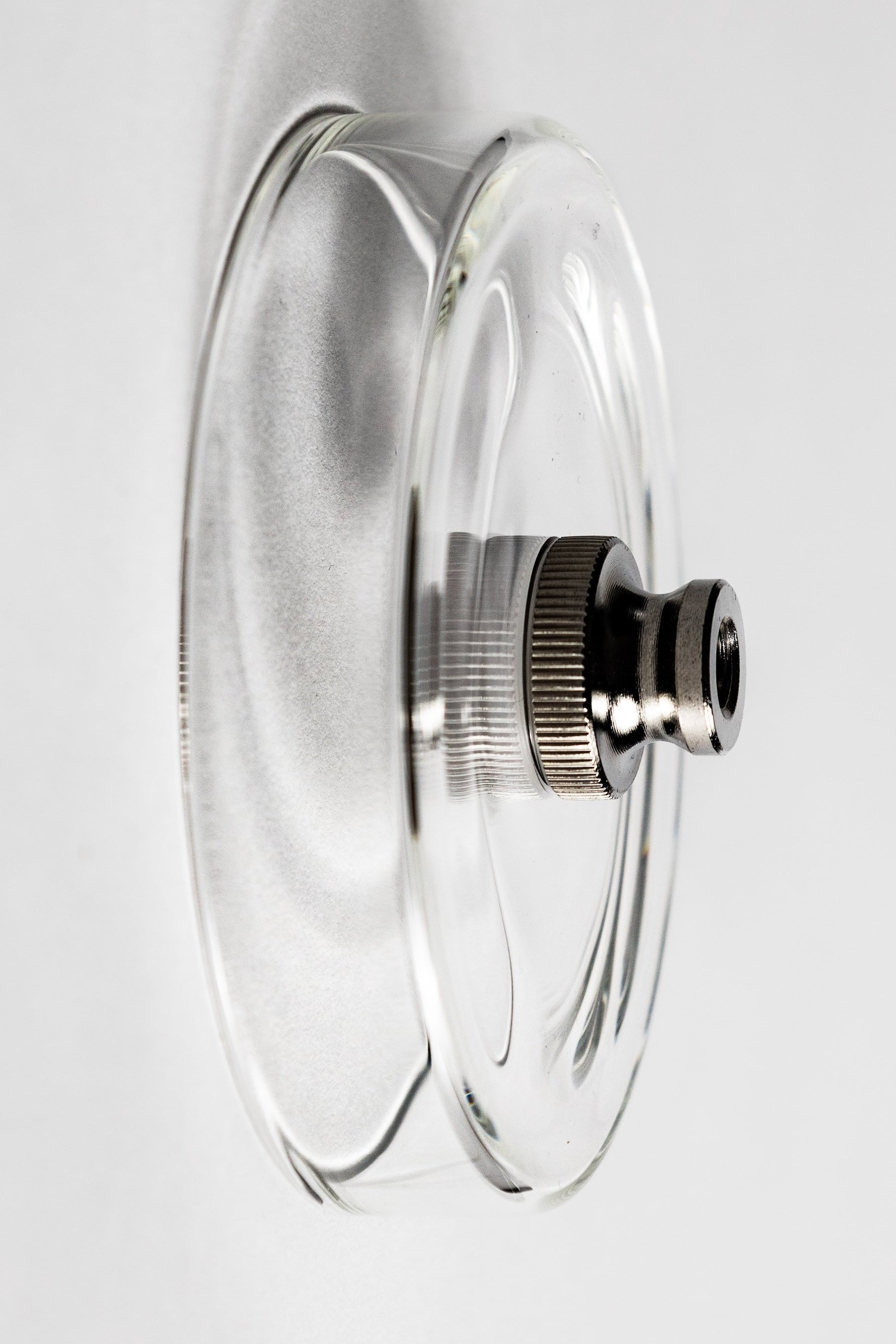 Clear glass lid with metallic knob on a white background