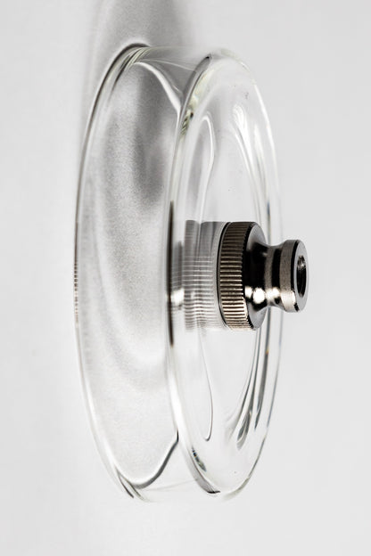Clear glass lid with metallic knob on a white background