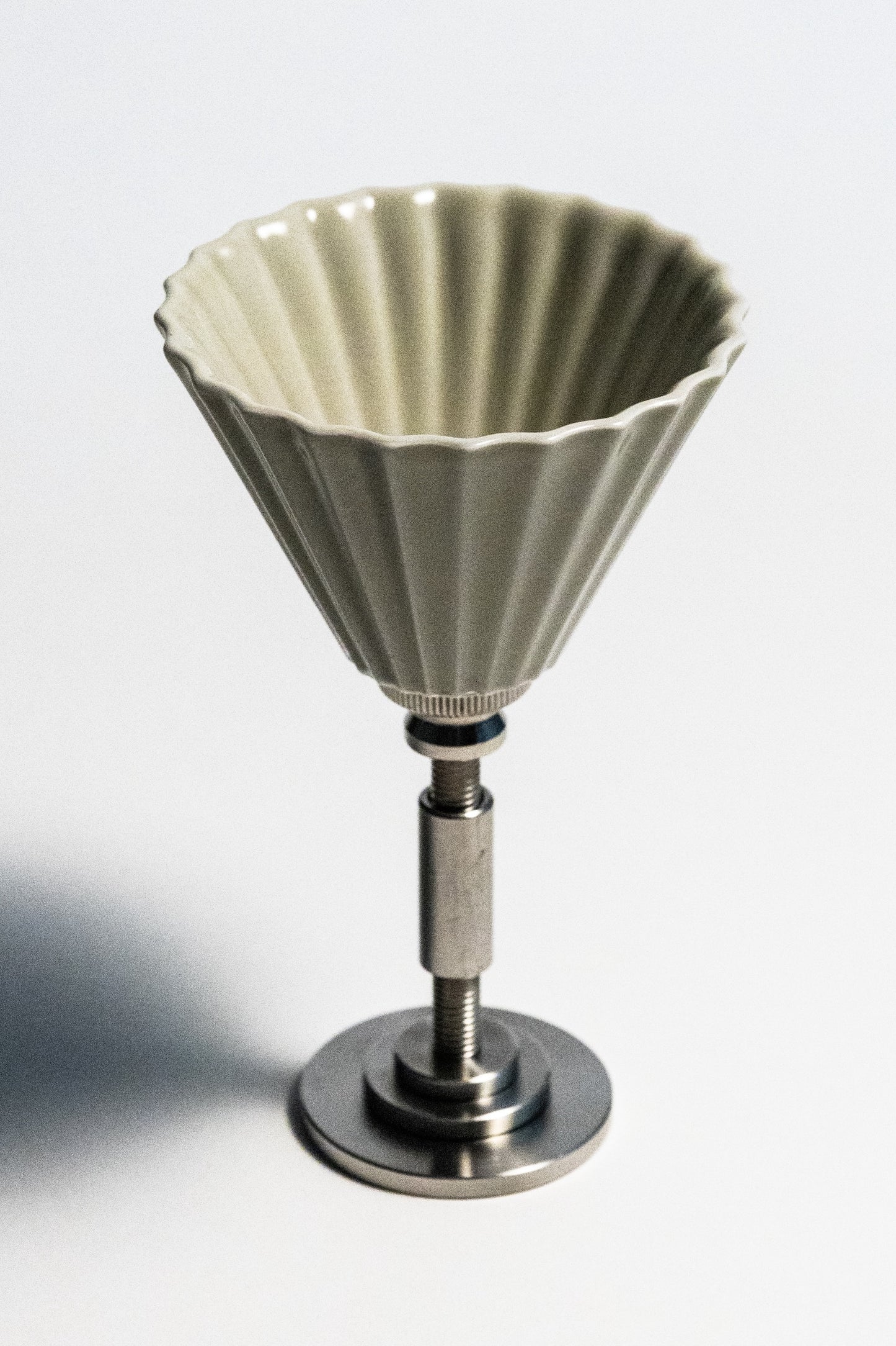 Ceramic coffee filter on a metal stand against a white background