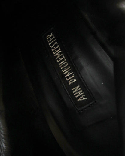 Close-up of a black leather jacket with a brand label on a dark background