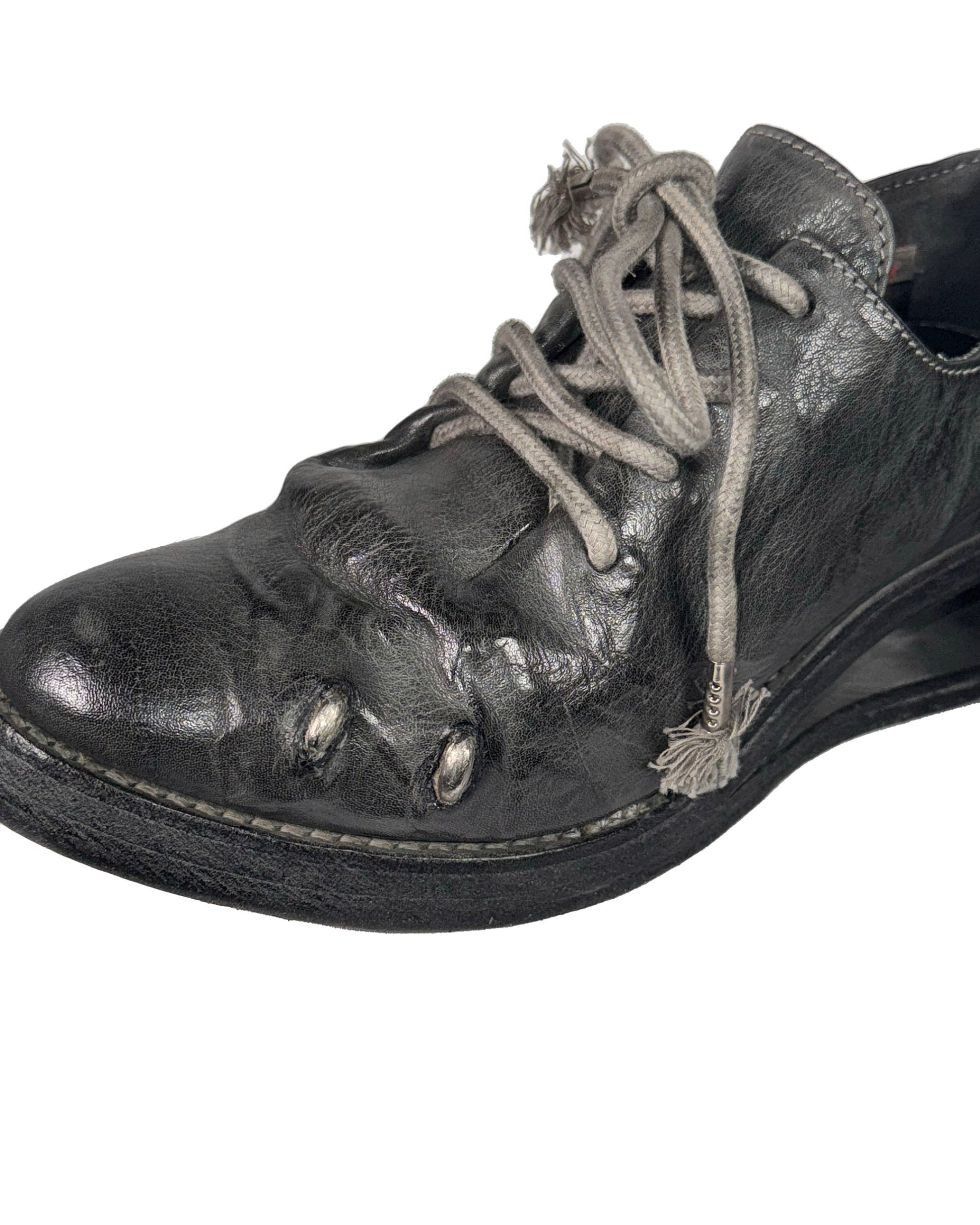 Black leather shoe with beige laces on a white background
