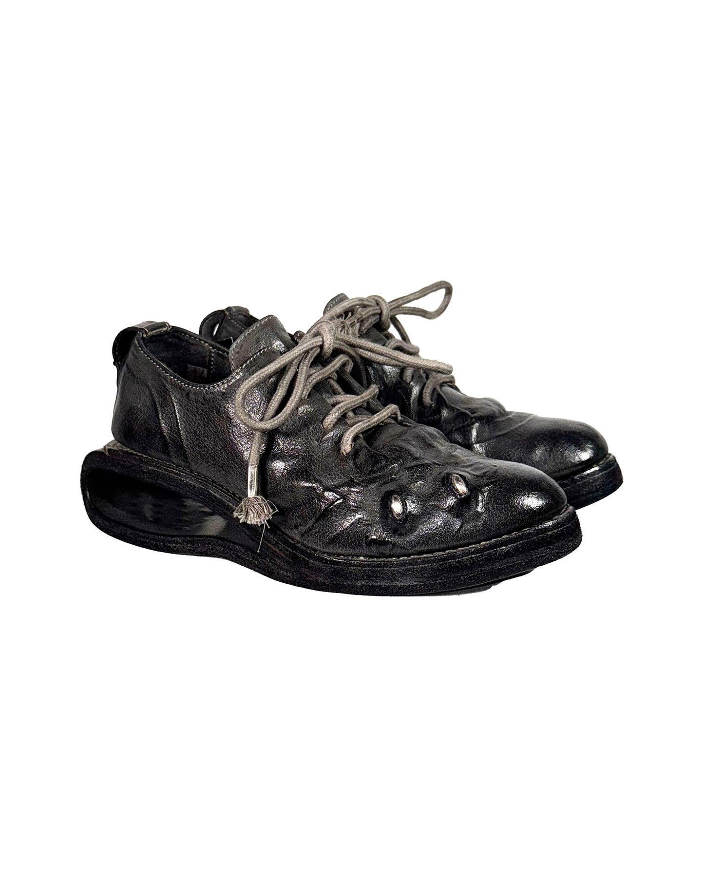 Pair of black leather shoes with worn soles on a white background