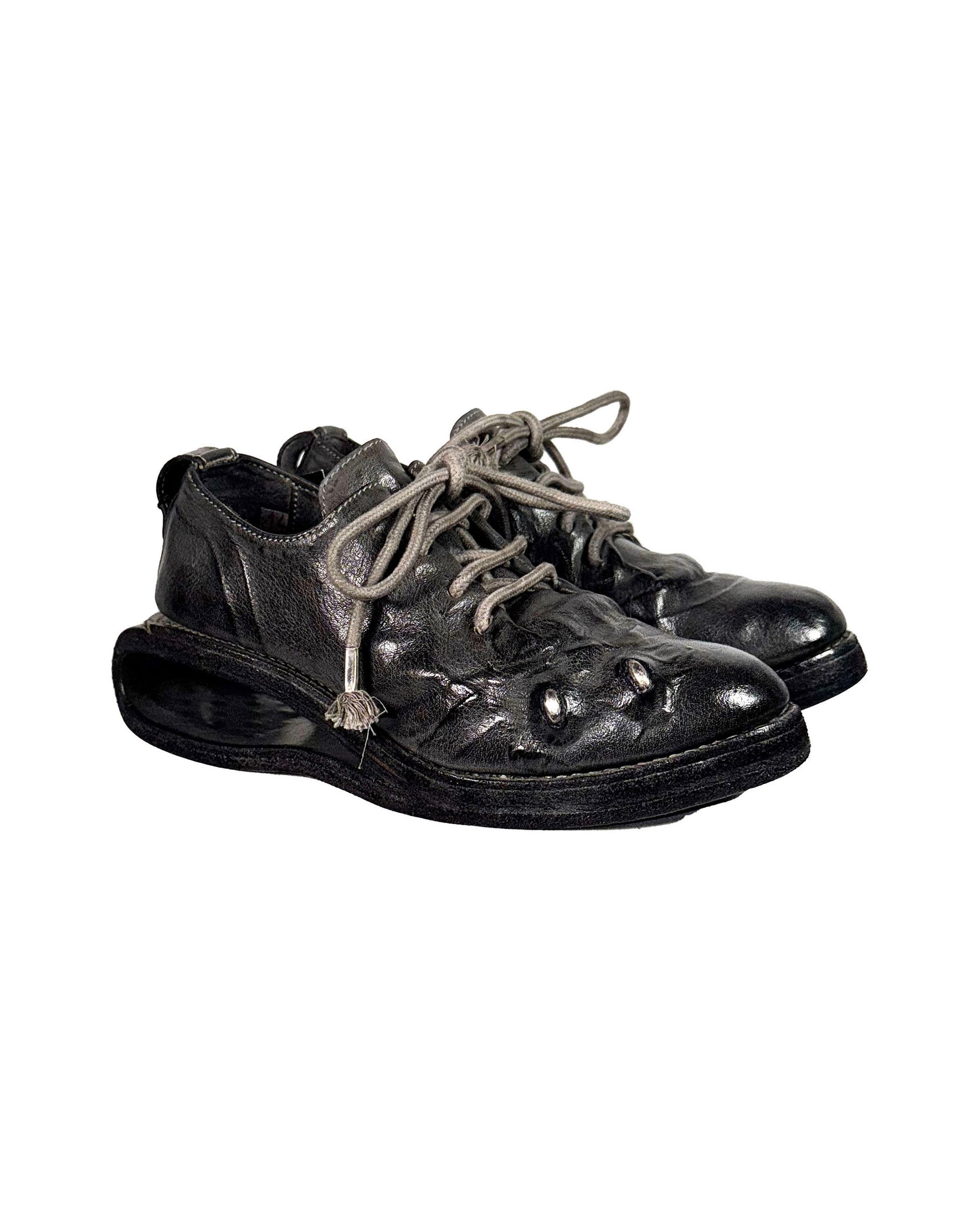 Pair of black leather shoes with worn soles on a white background