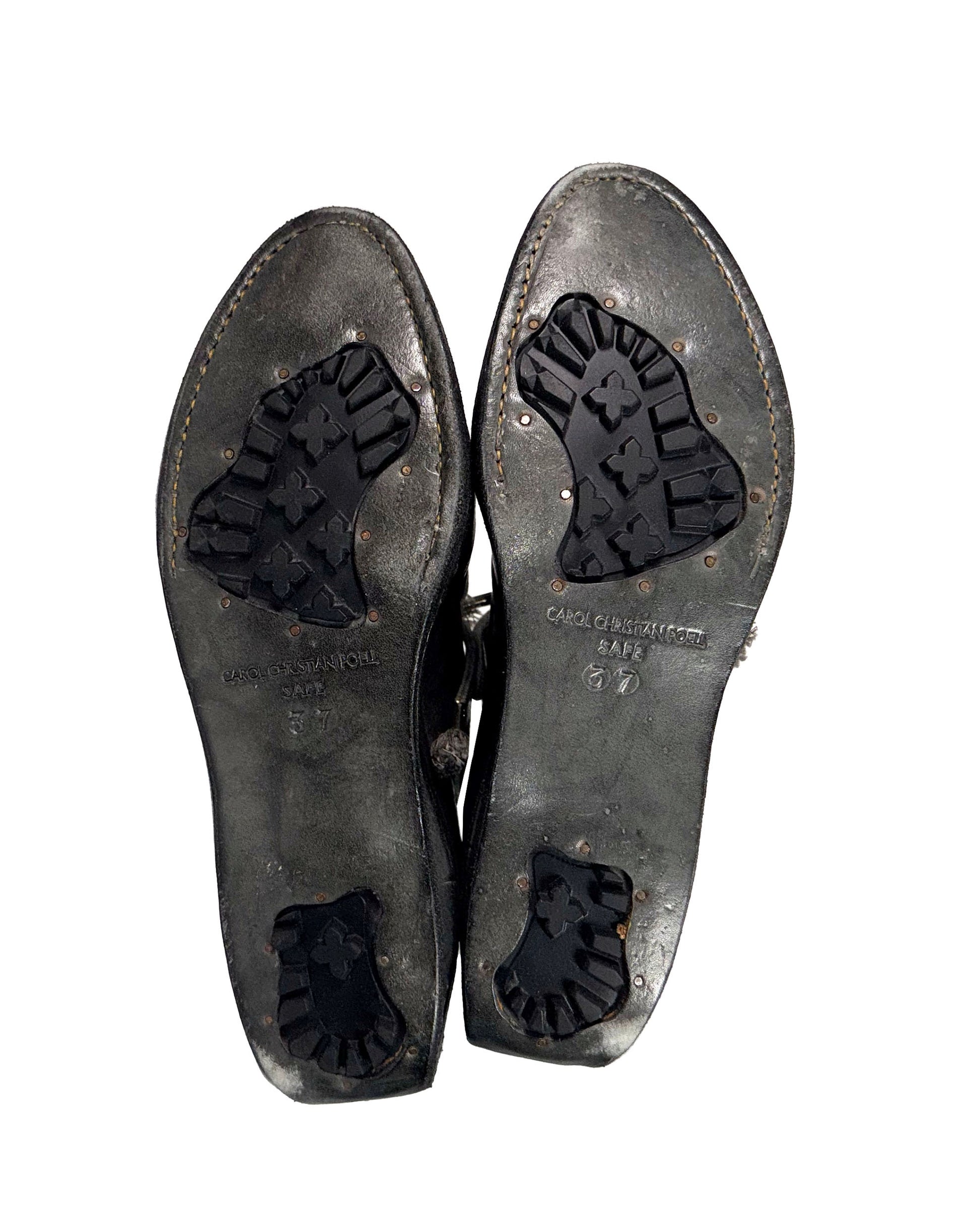Pair of worn leather shoes with visible brand name on a white background