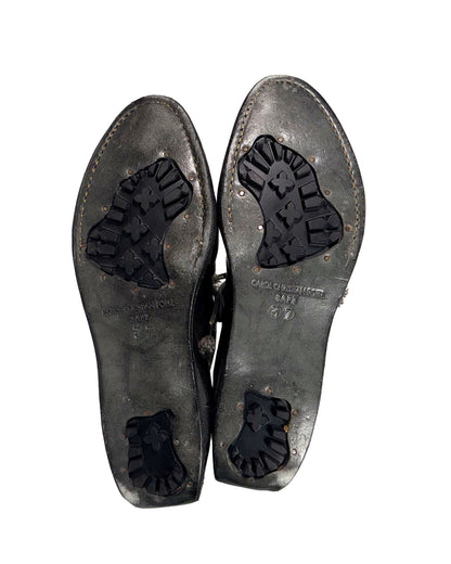 Pair of worn leather shoes with visible brand name on a white background