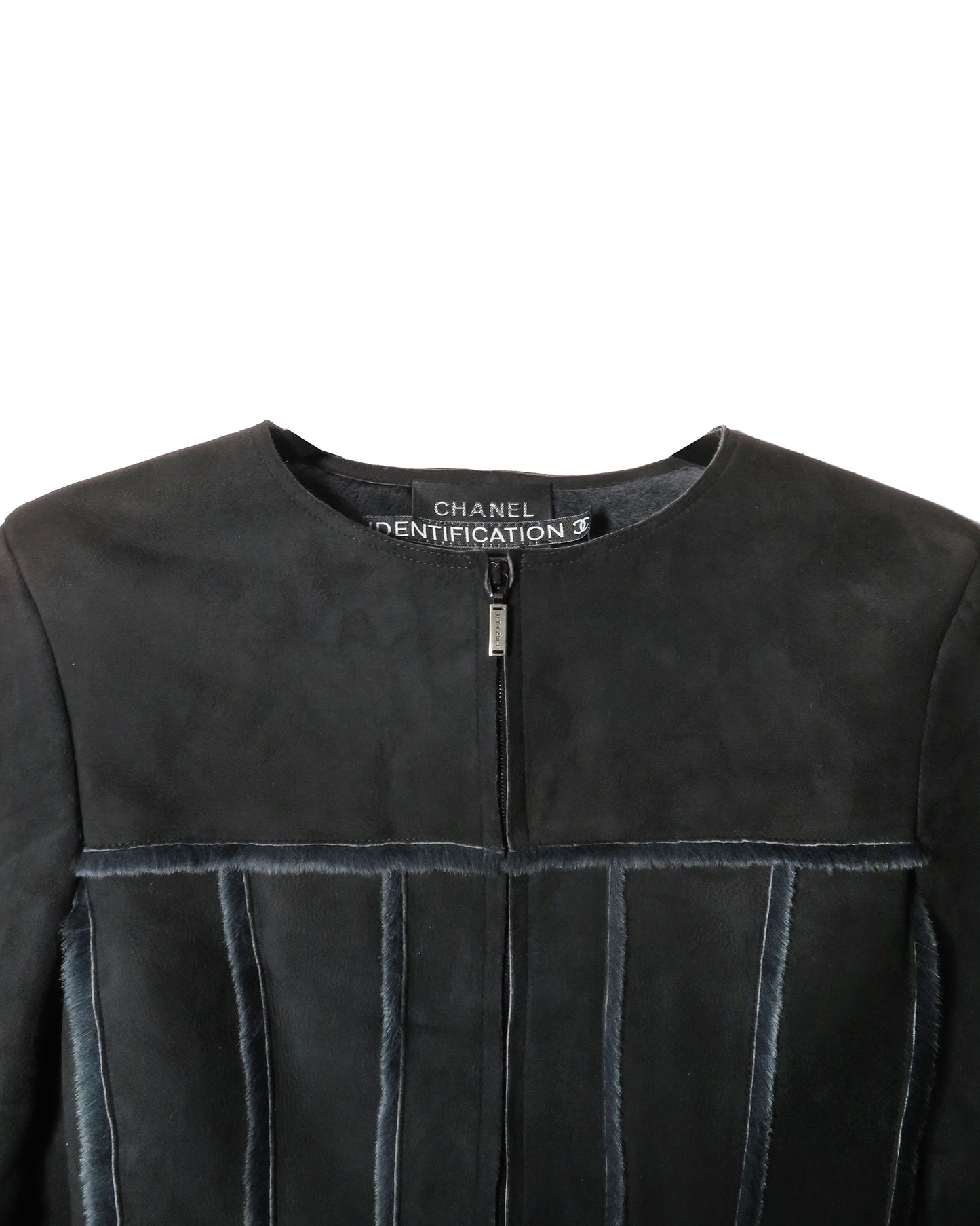 Close-up of a black leather jacket with Chanel branding on a white background