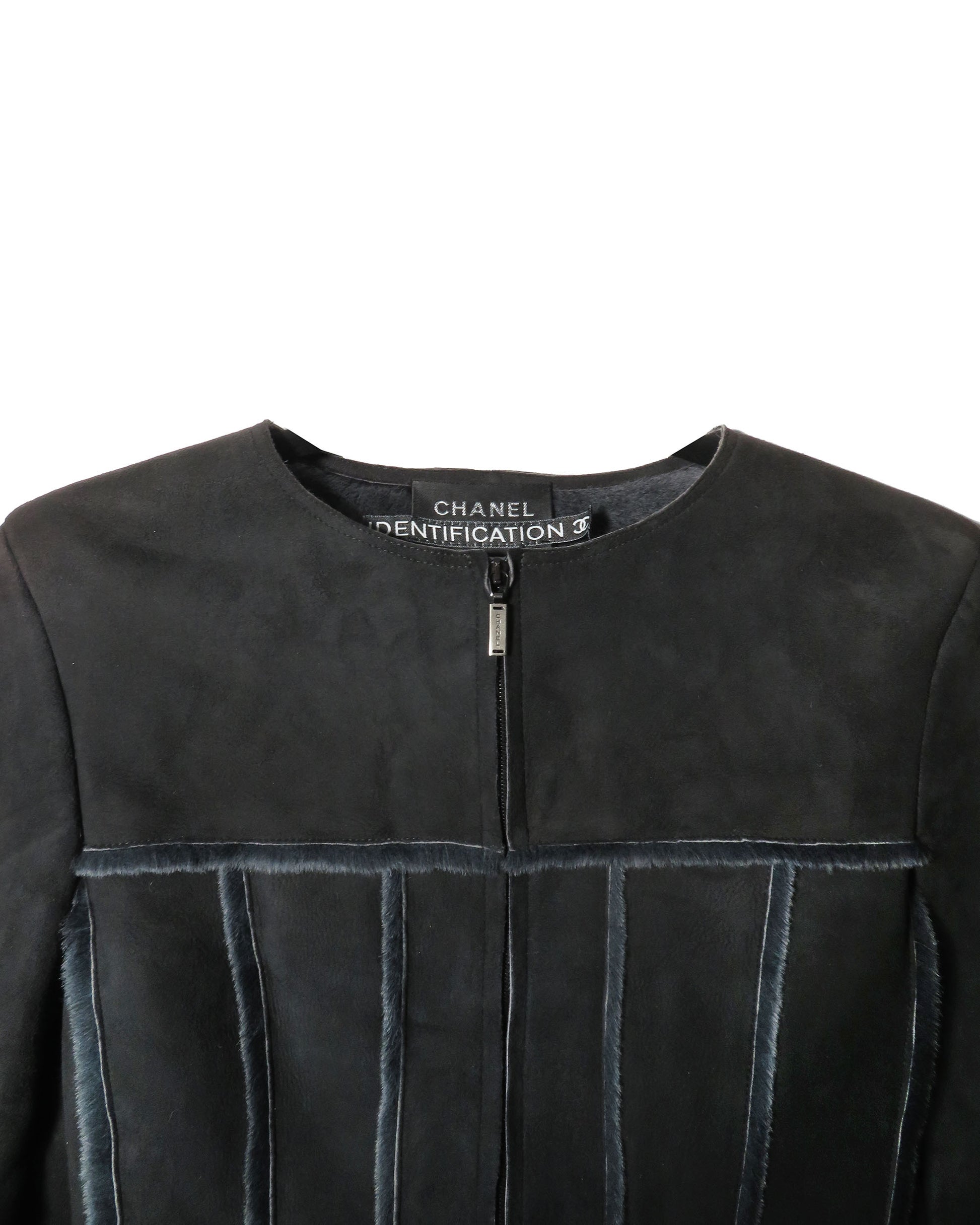 Close-up of a black leather jacket with Chanel branding on a white background