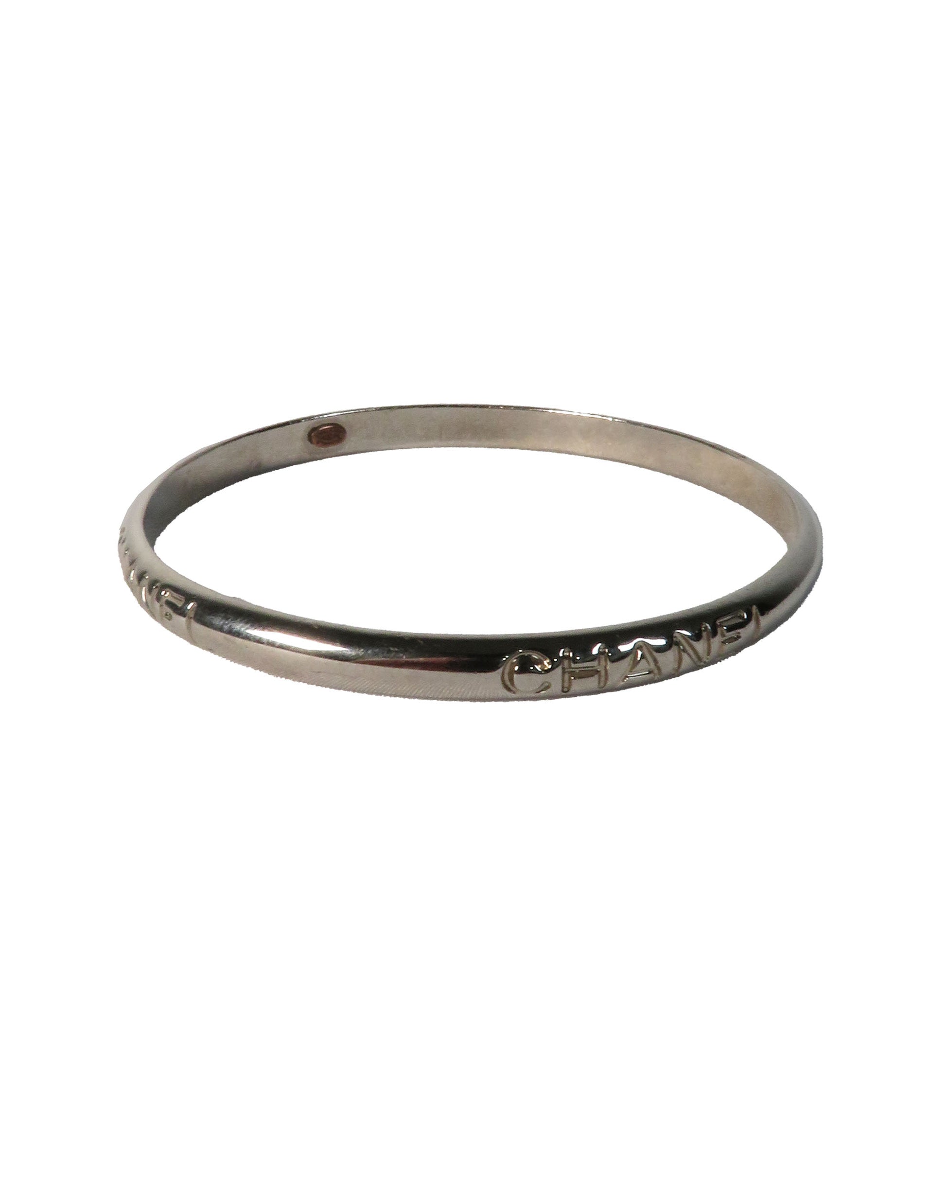 Silver bracelet with 'Chanel' engraving on a white background