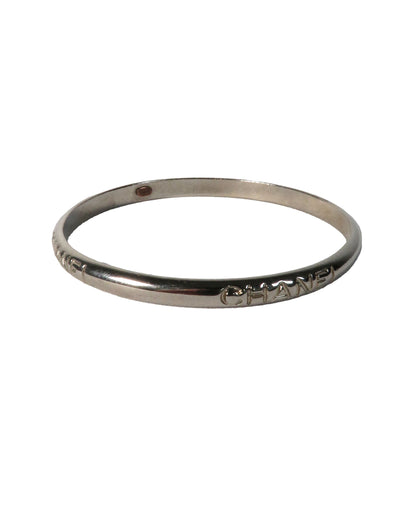 Silver bracelet with 'Chanel' engraving on a white background