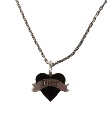 Heart-shaped Dior pendant on a chain against a white background