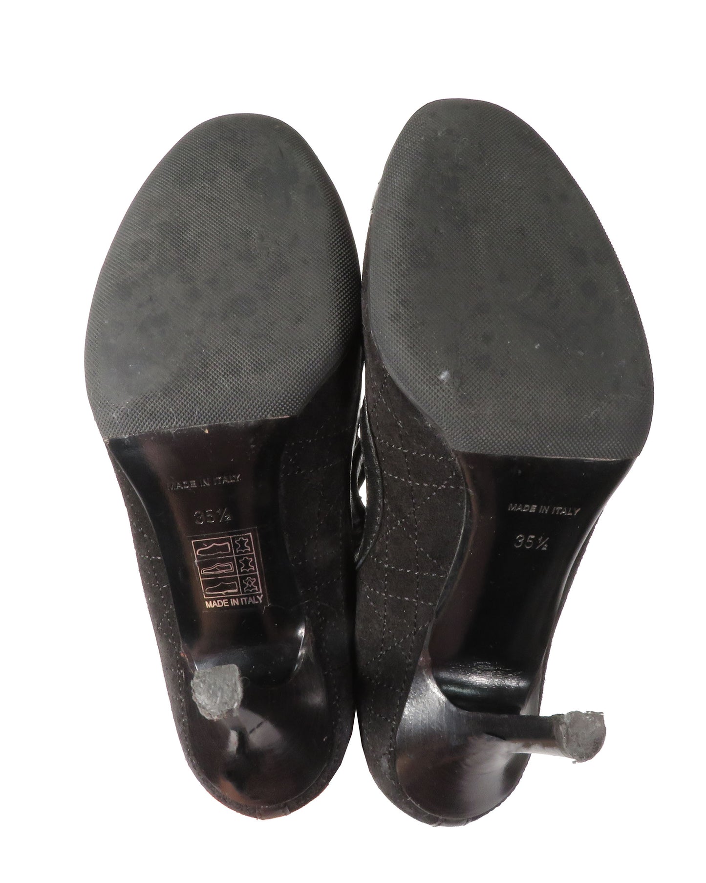 Black high-heeled shoes with soles facing up on a white background