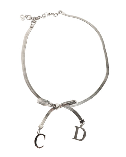 Necklace with a bow and 'CD' charms on a white background