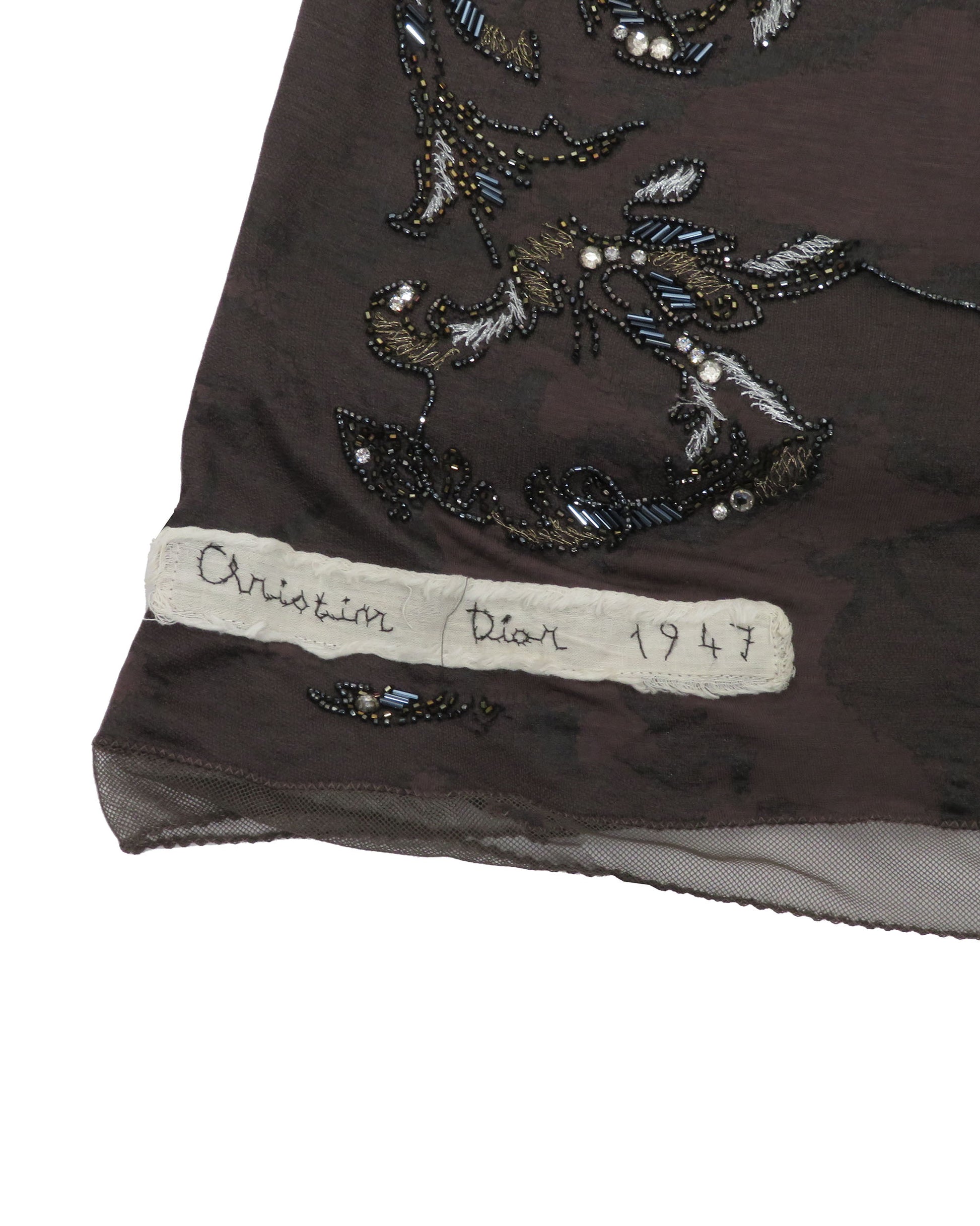 Embroidered fabric with 'Christian Dior 1947' label on a white background
