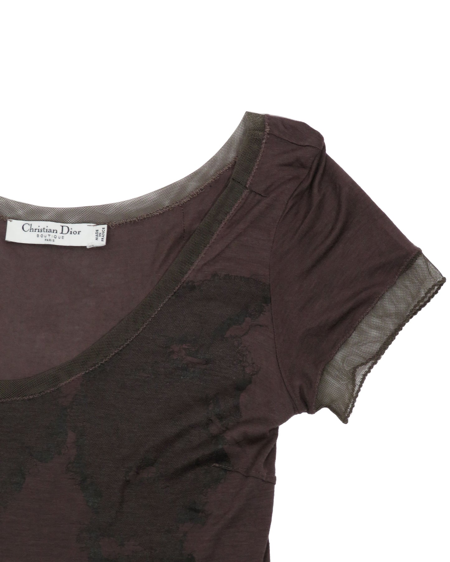 Close-up of a dark brown t-shirt with sheer sleeves on a white background, featuring a Christian Dior label.