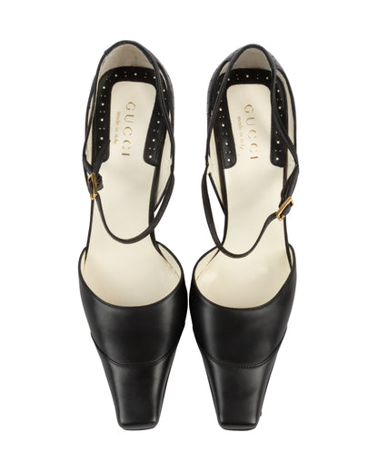 Pair of black high-heeled shoes with Gucci logo on a white background
