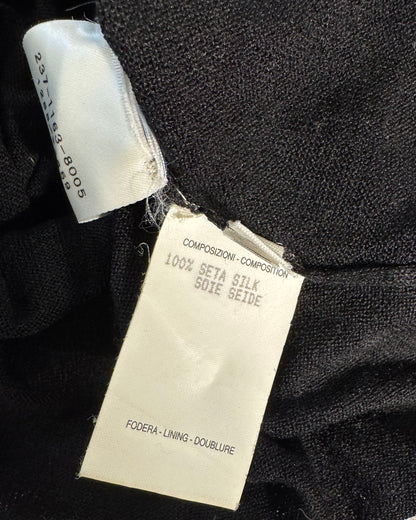 Close-up of a black fabric garment showing two tags: a white sewn-in size label and a larger white care/information tag reading '100% Seta Silk' and 'Foeda - Lining - Doublure'.