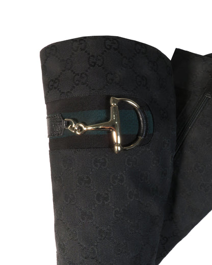Black Gucci-patterned fabric with a gold horsebit buckle on a white background