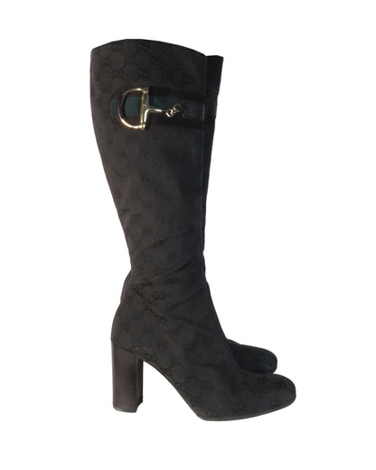 Black knee-high boot with gold buckle on a white background