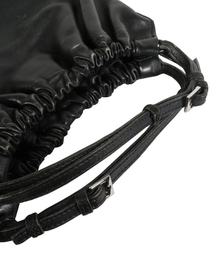 Close-up of a black drawstring bag with leather straps on a white background
