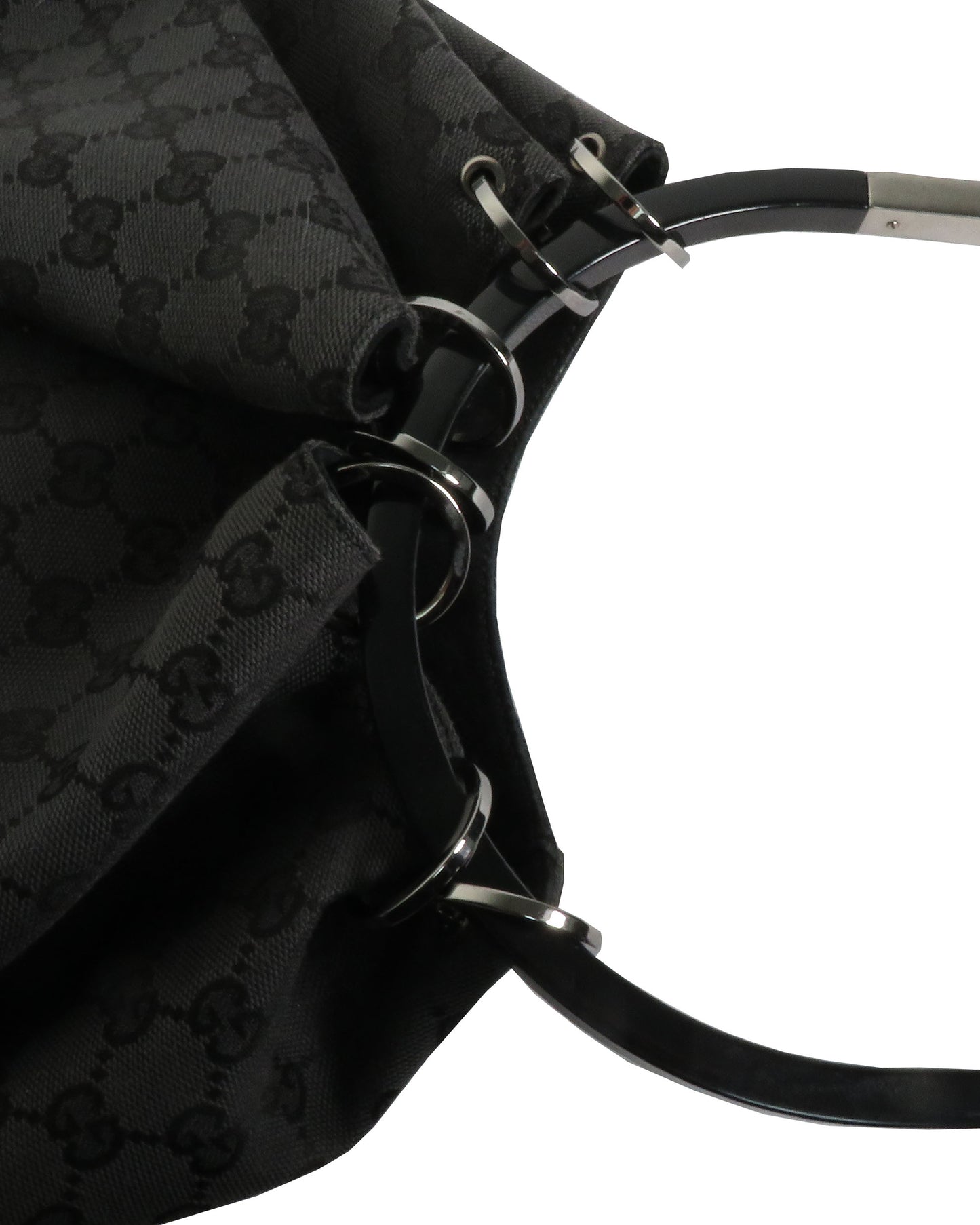 Close-up of a black patterned bag with metal hardware on a white background