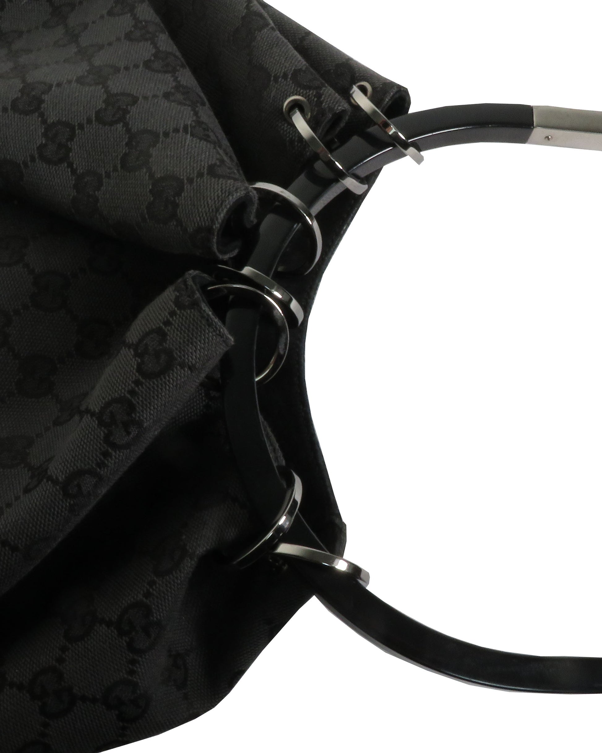 Close-up of a black patterned bag with metal hardware on a white background