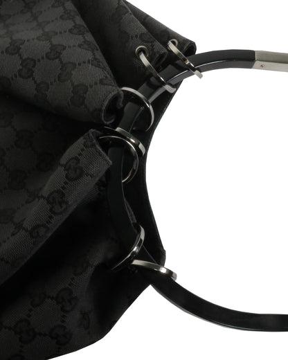 Close-up of a black patterned bag with metal hardware on a white background
