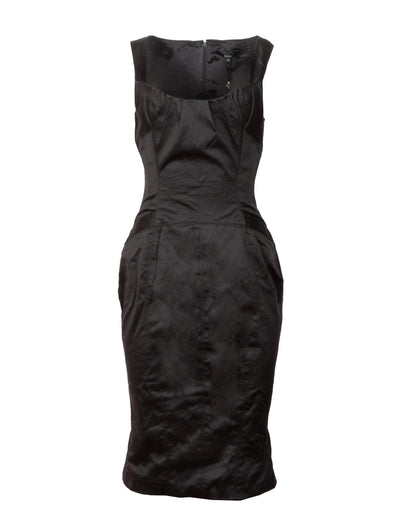 Black satin dress with a square neckline, paneled bodice, darted bust, sharply cinched waist, and gold-tone buckle detail on the hips. The dress has a back zip closure and appears to be made of cotton-elastane blend.