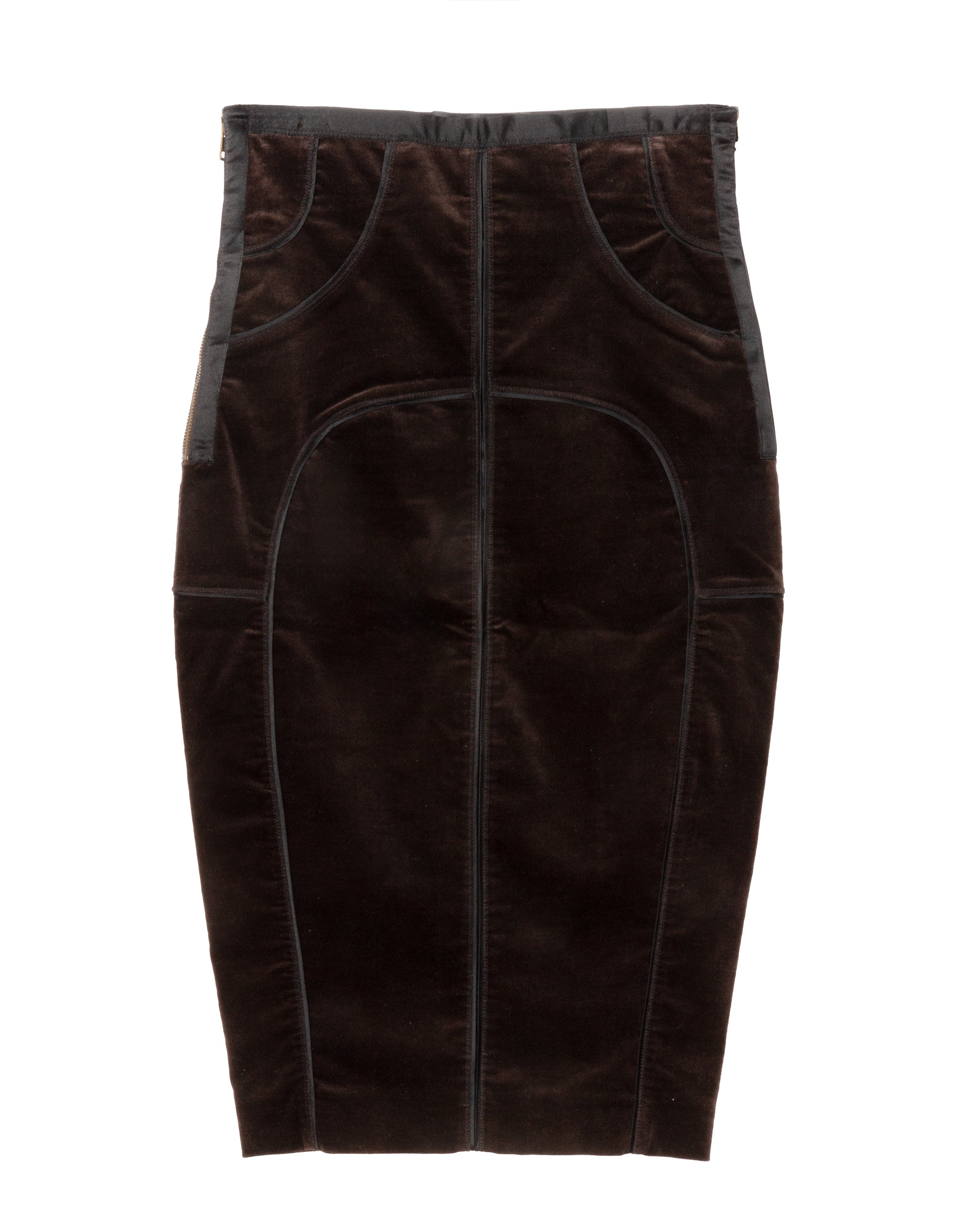 A dark brown velvet pencil skirt with curved seaming and structured panel construction. It features contrast satin trims along the waistband and side seams, a side zip closure, and a rear slit at the hem.