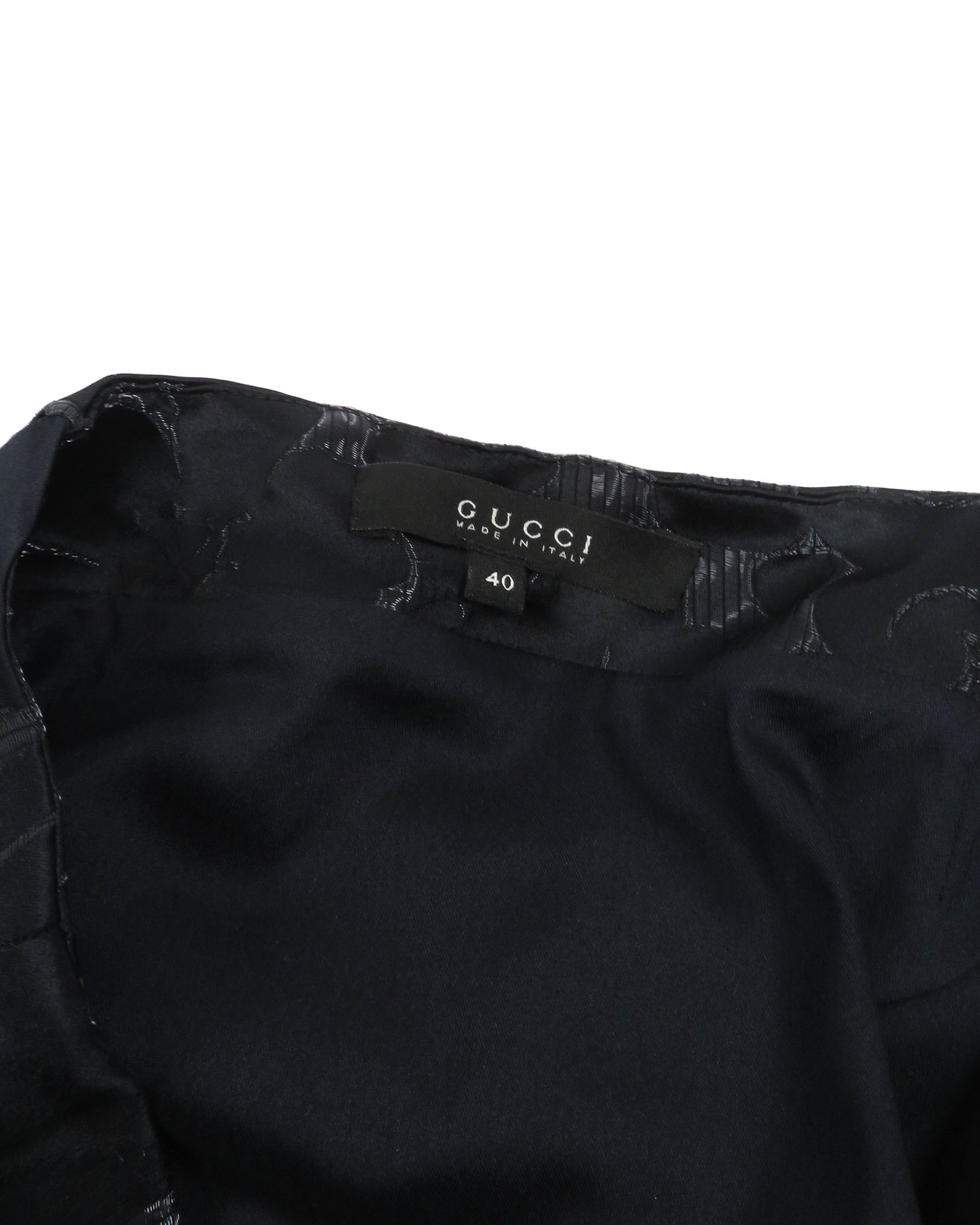 Black Gucci garment with tag on a white background