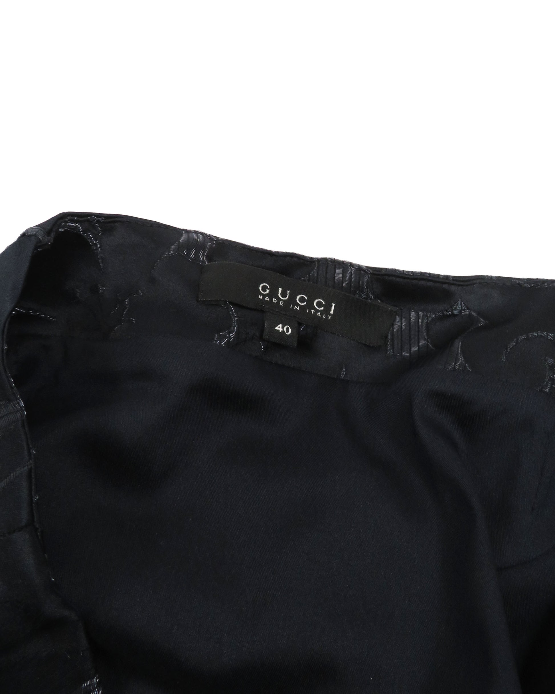 Black Gucci garment with tag on a white background