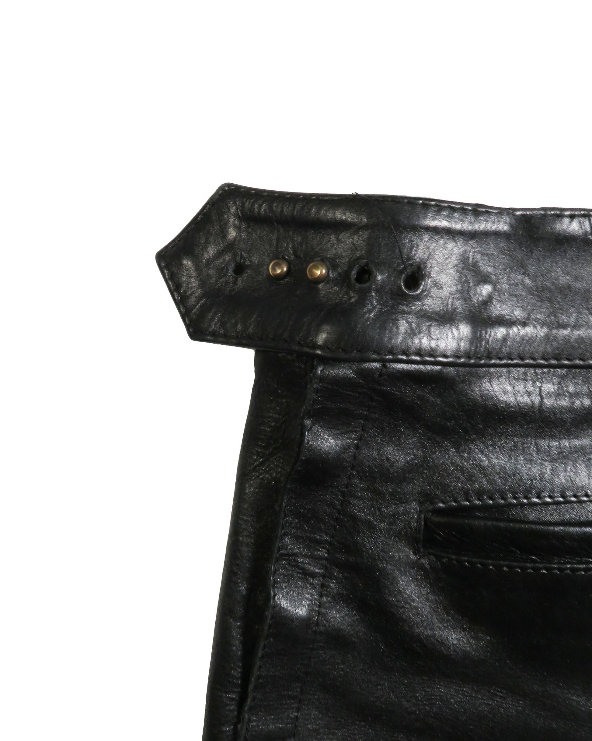 Close-up of black leather pants with stitching details on a white background