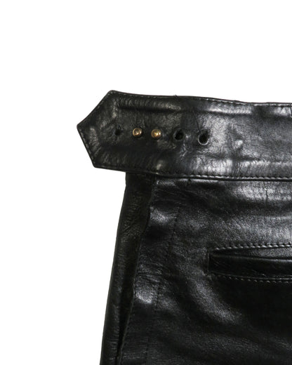 Close-up of black leather pants with stitching details on a white background