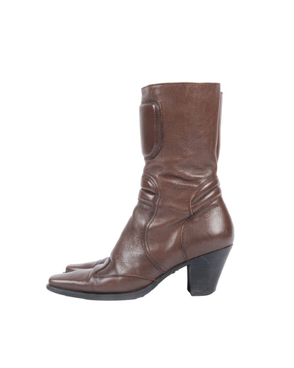 A brown leather mid-calf moto boot with a structured panel and padded details, featuring a squared-off toe and stacked block heel, with visible creasing and minor scuffing.
