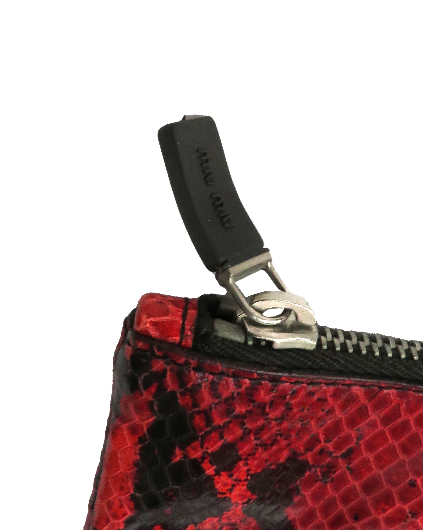 Close-up of a red and black patterned pouch with a zipper and black pull tab.