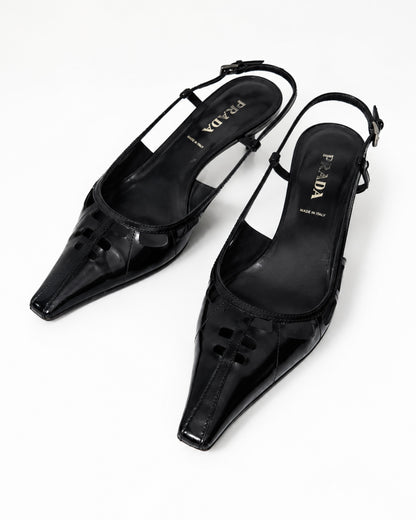 Black pointed-toe slingback heels on a white background