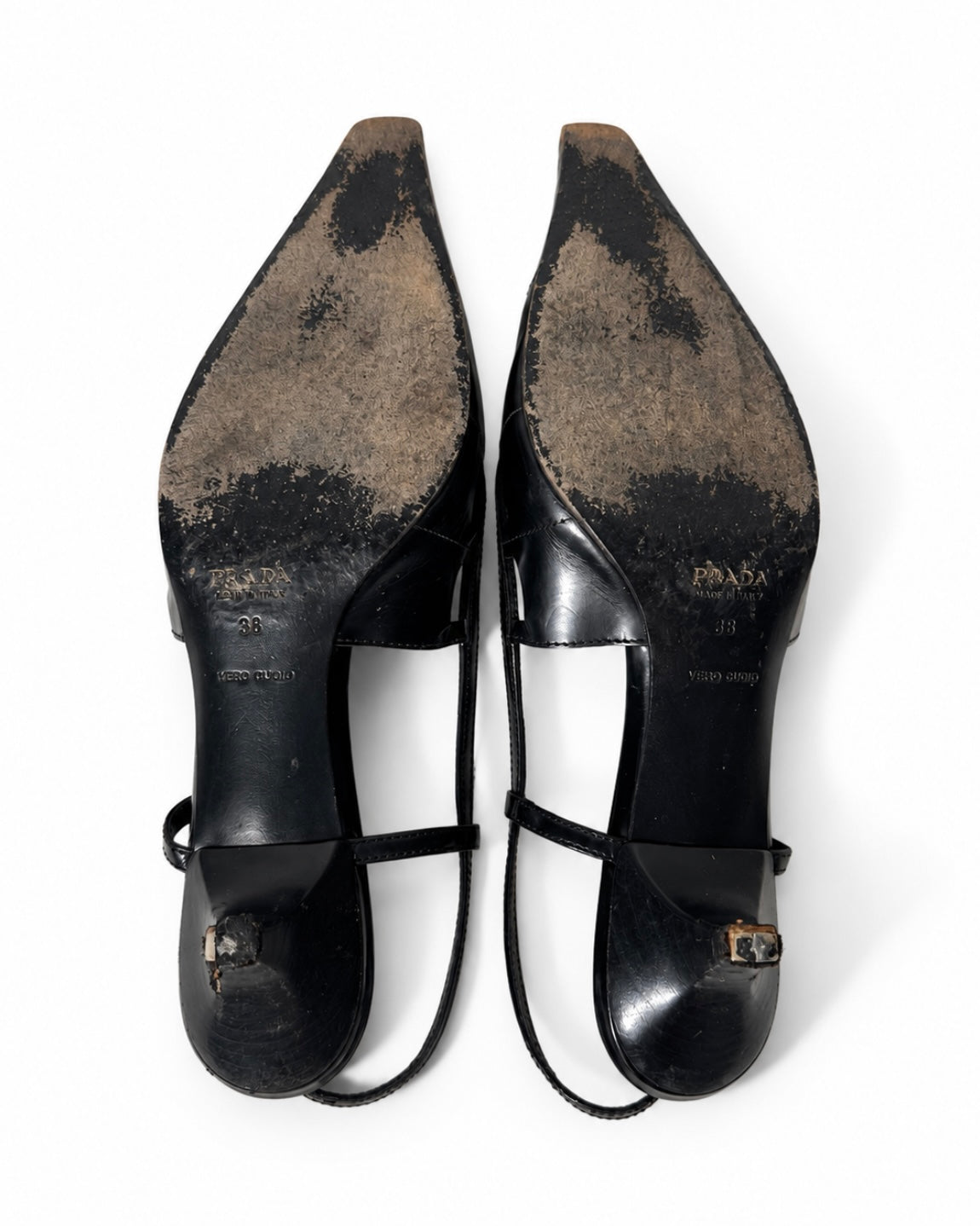 Pair of black high-heeled shoes with visible wear on a white background