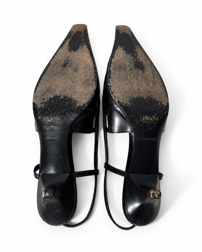 Pair of black high-heeled shoes with visible wear on a white background