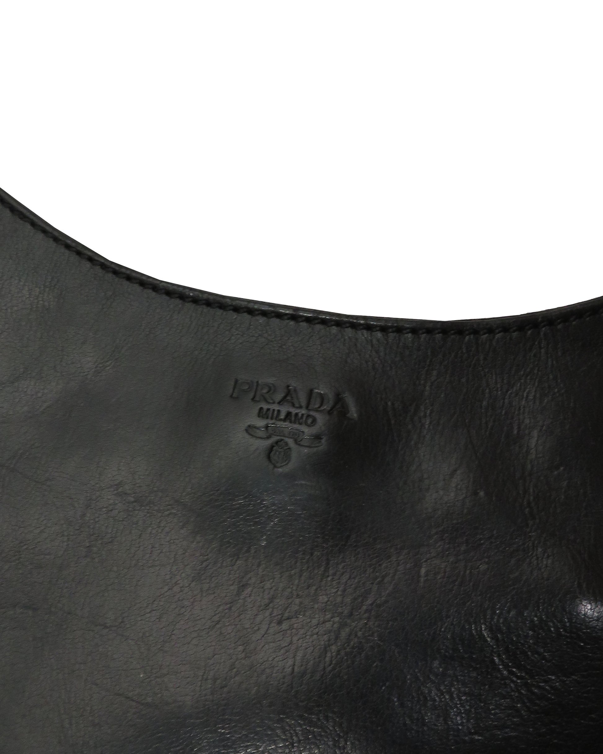 Close-up of a black leather handbag with Prada logo.