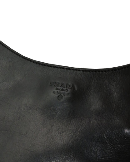 Close-up of a black leather handbag with Prada logo.