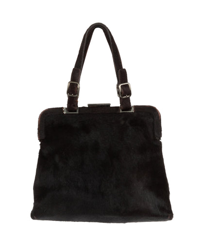 A dark brown fur frame bag with silver-tone hardware and dual adjustable handles. The bag is closed and displayed against a plain background.