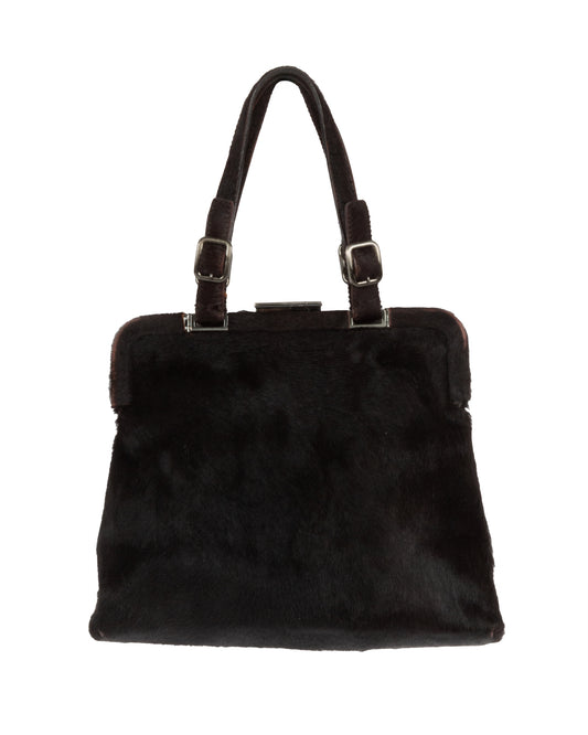 A dark brown fur frame bag with silver-tone hardware and dual adjustable handles. The bag is closed and displayed against a plain background.