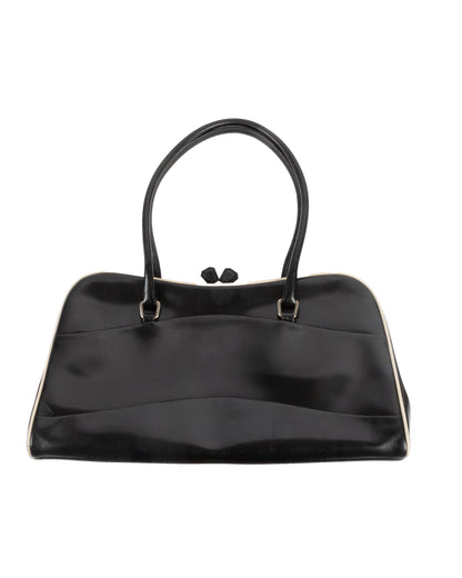 A black leather handbag with a kiss lock closure and double handles, featuring white piping along the edges and Prada's signature logo on the side.