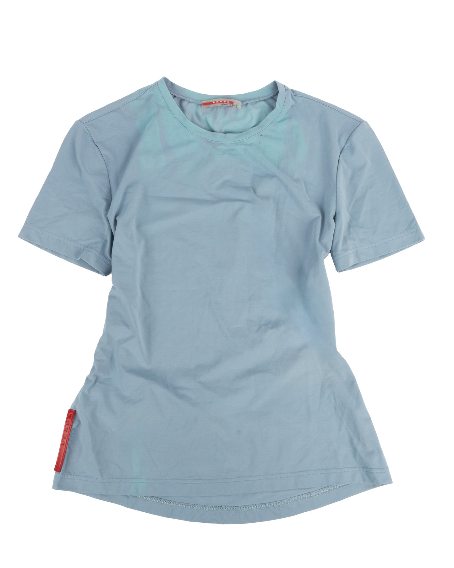 A powder blue short-sleeved technical t-shirt with a small zip pocket on the lower back and a red rubber Prada tag at the left hip.
