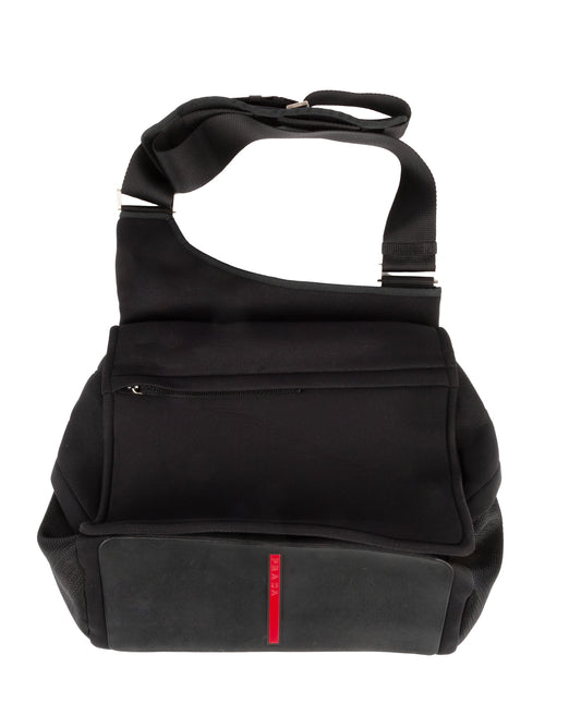 A black nylon shoulder bag with a red line detail on the front pocket and a rubber base.