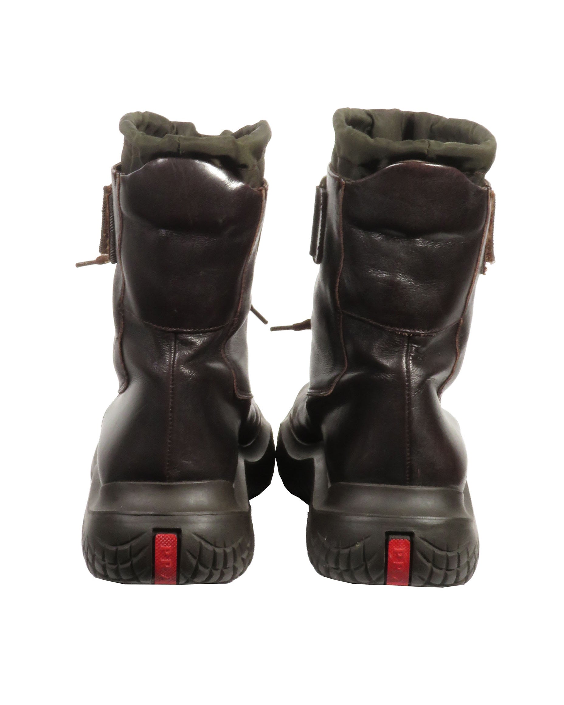 Pair of dark brown leather boots with red accents on a white background