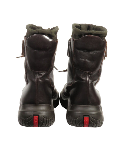 Pair of dark brown leather boots with red accents on a white background